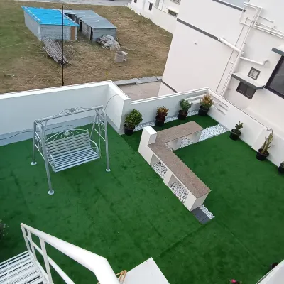 This high-angle shot captures the full scope of a rooftop garden I designed and installed. It features a large artificial lawn, a garden swing, and a built-in seating area.