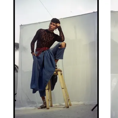 A full-body shot on 35mm film, showing the model perched on a stool. The raw, unpolished feel of the outdoor setup, complete with lighting stands, gives a behind-the-scenes authenticity to the fashion portrait.