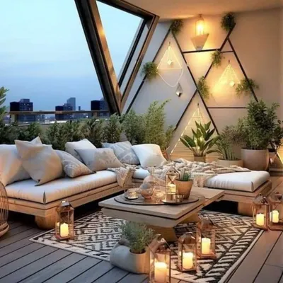A bohemian-inspired balcony design featuring low wooden seating, layered rugs, and an abundance of plants and lanterns. This setup creates a cozy and inviting space perfect for relaxing evenings.