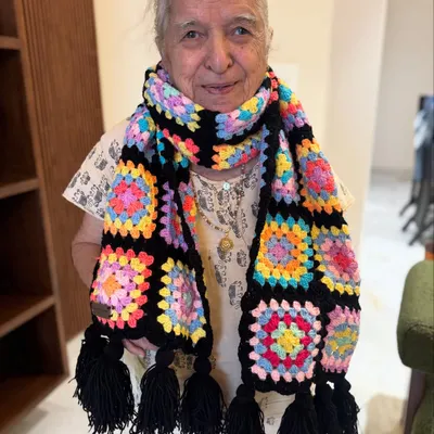 A classic granny square muffler with a bold black border that makes the colors pop. This design is a timeless favorite, finished with matching black tassels for a playful touch.