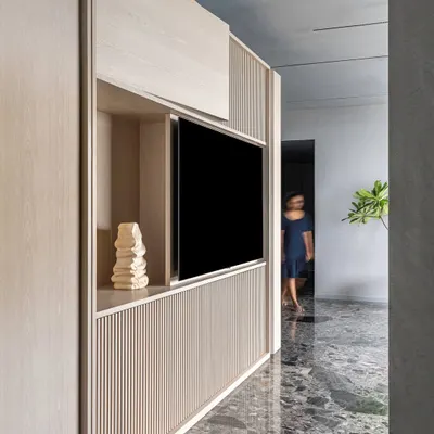 The kitchen block in 'A Wedged Haus' is designed as a monolithic object. Staggered woodwork accommodates utilities, while the light oak veneer finish allows it to stand as a sculptural element within the open-plan living space.