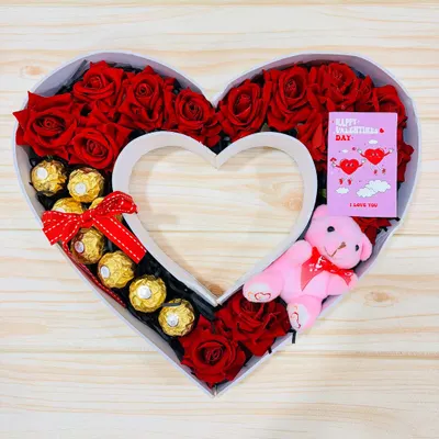 A hamper shaped like my heart. This monogram box is filled with red roses, Ferrero Rocher chocolates, a pink teddy bear, and a Valentine's card, making it a grand romantic gesture.