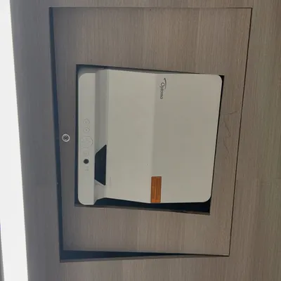 This is an ultra short throw projector, the Optoma AZH430UST, installed in a modern conference room. Its design allows it to be placed very close to the wall, which is perfect for meeting rooms where space is limited.