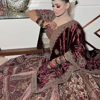 This deep maroon velvet lehenga is designed for a grand winter wedding. It features intricate all-over embroidery and is paired with a matching velvet dupatta for a truly royal bridal statement from head to toe.