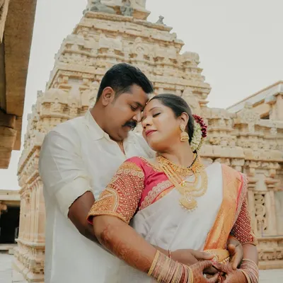 A beautiful, intimate portrait of a couple in traditional South Indian attire, set against the magnificent backdrop of a heritage temple. This shot perfectly blends cultural richness with romantic connection.