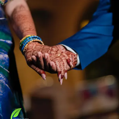 A beautiful moment captured between the bride and groom, showing a glimpse of their mehendi-adorned hands.