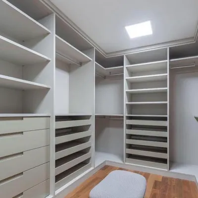 This image showcases the internal configuration of a custom walk-in closet before the doors are installed. Notice the variety of storage options, including pull-out shoe racks, deep drawers, and double hanging rods, all designed to the client's specifications.