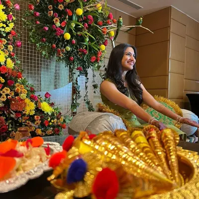 A happy client at her mehendi ceremony, surrounded by beautiful floral decorations. It's all about the festive vibes.