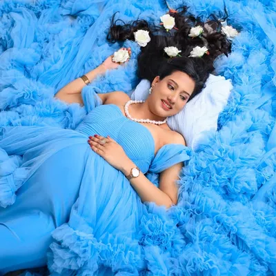 A dreamy, angelic portrait of the mom-to-be. Lying on a bed of the gown's blue tulle with white roses in her hair, this shot is pure elegance and serenity.