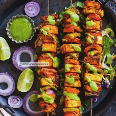 Skewers of colorful Paneer Tikka, featuring marinated cottage cheese, bell peppers, and onions. Grilled live at your event, these starters are served hot with a drizzle of mint chutney for a burst of fresh flavor.