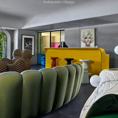 The living room of Project 86 is all about creating a fun, casual atmosphere with iconic furniture. The space is sectioned into a TV lounge, an informal living area, and a bar, all tied together with an ombre wall effect and bold art.