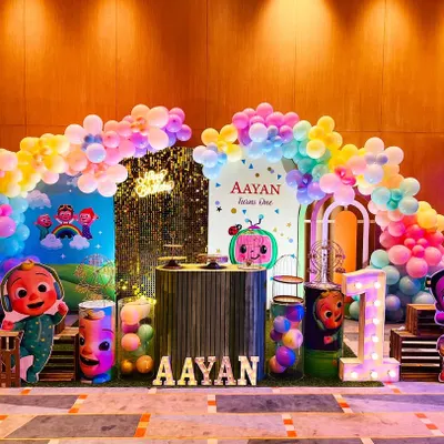 This Cocomelon-themed birthday party is full of color and fun. The setup includes a vibrant backdrop with all the characters, themed pedestals, and a light-up name sign for the birthday boy.