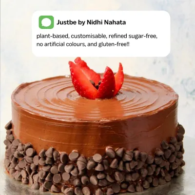 A close-up of my plant-based chocolate cake, topped with a beautifully carved strawberry. The text bubble highlights what I stand for: customisable, refined sugar-free, and gluten-free options, all made with natural ingredients.