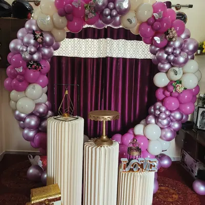 This romantic indoor setup features a beautiful balloon ring in shades of magenta, purple, and white. Paired with elegant pedestals and a 'LOVE' sign, it serves as a perfect photo booth or backdrop for an engagement party, anniversary, or valentine's surprise.