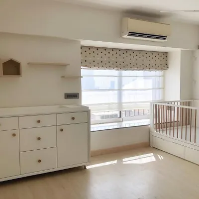 This modern nursery is bright, airy, and peaceful. I designed the furniture, including the crib with storage and the dresser, in a clean white finish with natural wood handles to create a timeless and neutral space.