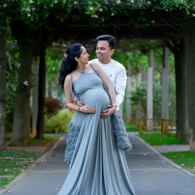 A beautiful couple's portrait taken under a floral archway in a Bangalore park. The soft grey gown complements the natural green surroundings perfectly.