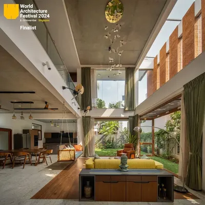 A complete view of the main living area in "A Home by the Park," showcasing the interplay of volume, light, and nature. The butterfly chandelier adds a whimsical touch to the exposed concrete ceiling.