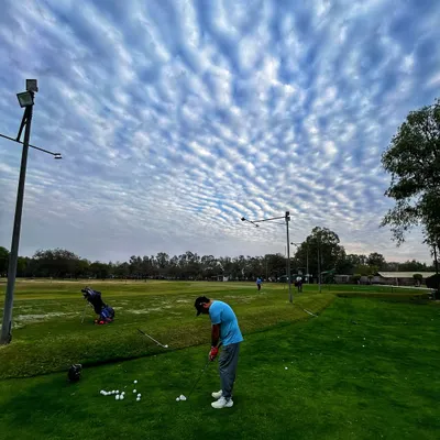 A golfer gets his practice in under a dramatic sky. Every shot is a chance to get one percent better.