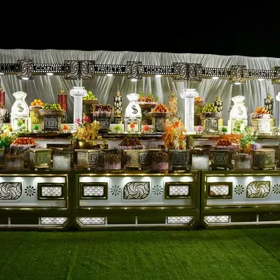 A lavish and beautifully lit dessert and fruit buffet. The symmetrical arrangement and ornate white and gold counter create a stunning display that invites guests to indulge.