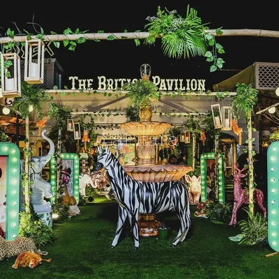 A full view of the Mickey Mouse jungle safari setup at The British Pavilion. The space is filled with life-sized animal props, illuminated character frames, and lush greenery, creating a truly wild and adventurous atmosphere.