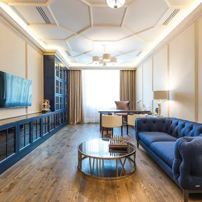 A wide view of a luxurious executive office I designed. The space features a custom floor-to-ceiling storage unit in a deep blue, a classic Chesterfield sofa, and an intricate coffered ceiling with integrated lighting for a timeless look.