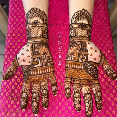 A classic Rajasthani bridal mehendi featuring intricate jharokha windows and peacock motifs. The design is symmetrical across both hands, creating a stunning, regal look for the modern bride.