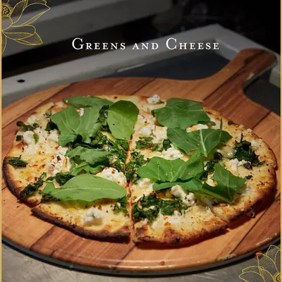 Our live-baked pizzas are always a hit. This one, topped with fresh arugula and crumbled cheese, showcases our commitment to using quality ingredients for a superior taste.