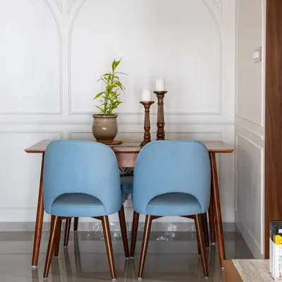 A simple yet elegant dining nook. The pop of color from the blue velvet chairs against the classic wall molding and warm wood table creates a charming space for intimate meals.