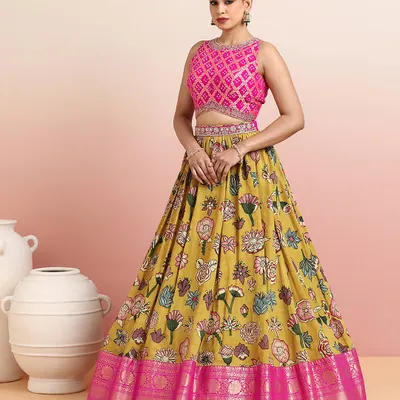 This vibrant mustard yellow lehenga with bold floral prints is a celebration of color and craft. The contrasting pink Bandhani-inspired blouse and rich zari border make it a perfect choice for a mehendi or sangeet ceremony.
