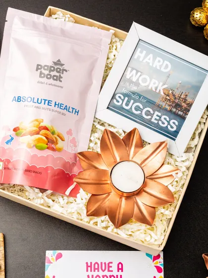 This motivational hamper is designed to inspire. It includes a "Hard Work is the Formula for Success" photo frame, a pack of healthy fruit and nuts, and a copper flower t-light holder.