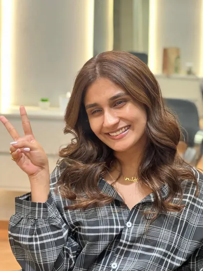 A happy client showing off her new beige brown balayage. The color brightens her complexion and her smile shows her confidence.