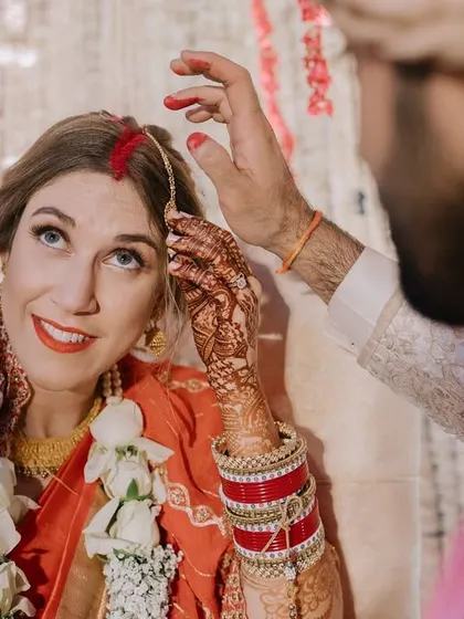 An intimate close-up as the groom applies the sindoor. The bride's upward glance and smile make this a deeply personal and touching photograph.