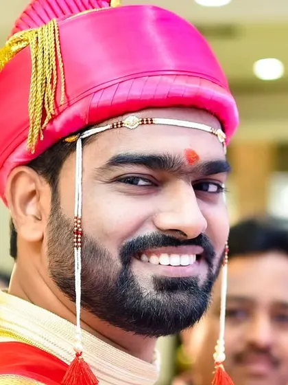 A candid, happy portrait of the groom in his vibrant pink pheta, looking back with a bright smile during the festivities.