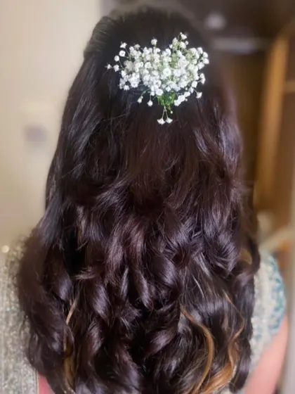 A simple half-updo with soft waves, decorated with a sprig of fresh baby's breath for a delicate touch.