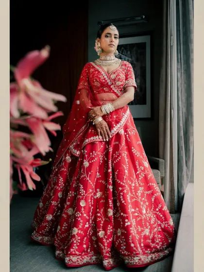 A full-length view of the bride in her breathtaking red lehenga. The makeup is designed to complete this regal and timeless look.