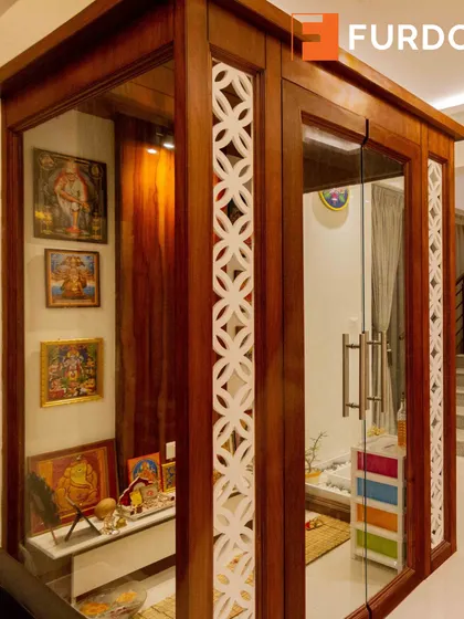 A side view of the traditional pooja room, highlighting the intricate jali work and the warmth of the wooden structure.