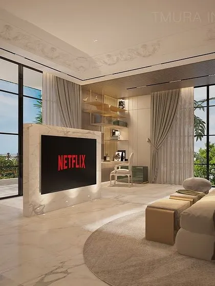 The custom-designed TV unit in this bedroom stands as a monolith of marble, elegantly dividing the space. The floor-to-ceiling windows are dressed with heavy curtains, allowing for complete light control.