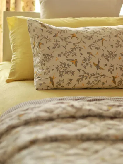 A close-up of our 'Winged Skies' quilted pillow sham. The detailed print features delicate branches and birds, bringing a touch of nature and whimsy to your bedding ensemble.