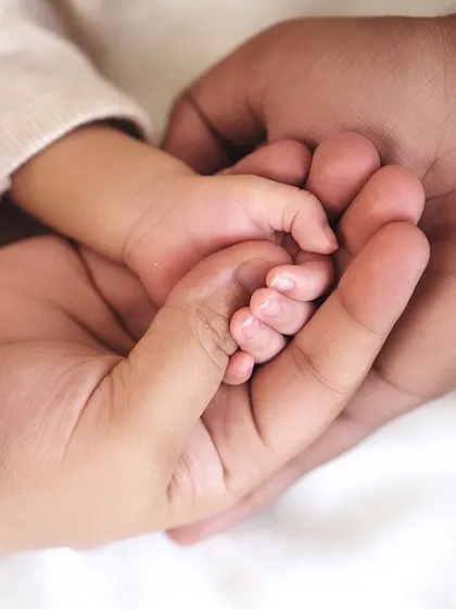 A newborn's hand resting safely in their parents' hands. This shot beautifully illustrates the scale of how small and delicate your new baby is.