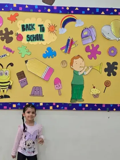 Two friends on their first day, standing in front of our colorful 'Back to School' bulletin board.