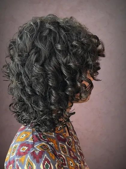 A side view of Vageesha's curl transformation, showing the volume and shape created with a layered cut.
