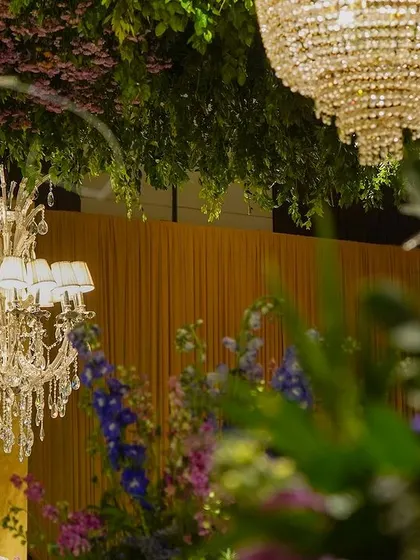 A detail shot of a chandelier hanging from the green canopy, framed by out-of-focus flowers.