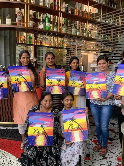 A happy group from Trio Technologies shows off their sunset paintings at RCB Cafe in Bangalore. This is the classic sip and paint experience: good vibes, guided art, and a masterpiece to take home.