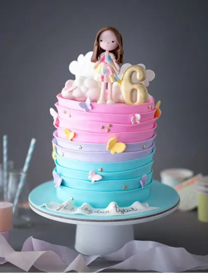 A colorful and vibrant cake for a 6th birthday. This pastel ombre cake is adorned with butterflies and a cute girl figurine.