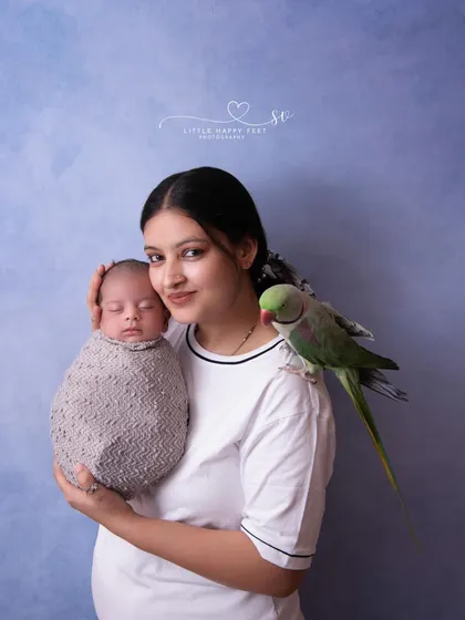 A mother's love, with a feathered friend watching over. This unique portrait includes the family's pet parrot, showing that all family members are welcome.