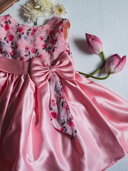 A beautiful blend of floral and satin. This pink party dress features a lovely floral print on the bodice and bow, paired with a shimmering pink satin skirt that’s ready for any celebration.