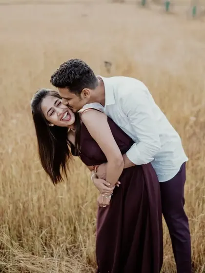A playful and joyous moment in a golden field, capturing the bride's laughter and the couple's carefree spirit.