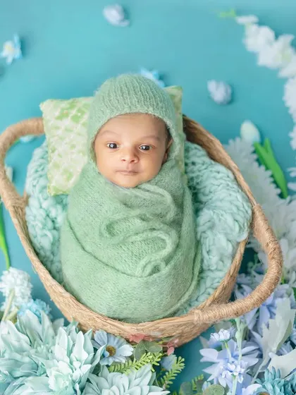 An awake newborn looking curiously at the camera from his cozy basket.