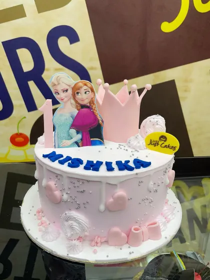 A 2kg pink Frozen cake for a first birthday, featuring Anna and Elsa with a princess crown.