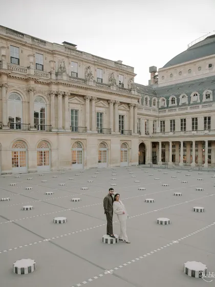 A full view of the couple standing on the iconic columns of the Palais Royal, a shot that feels straight out of a fashion magazine.